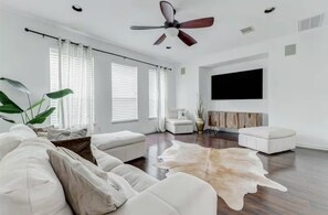 A spacious living room with a white sofa, a leather rug, and a ceiling fan. - EaDo Treasure with Private Garage Near Downtown and Stadiums (Houston)
