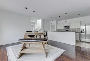 A modern kitchen with white cabinetry, stainless steel appliances, and a central island. - EaDo Treasure with Private Garage Near Downtown and Stadiums (Houston)