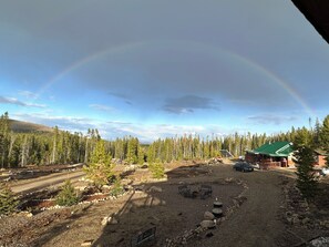 Ländliche Landschaft mit einem Haus, einem Feldweg und einem Regenbogen.