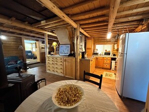 En inredning med träpanel, ett matbord, stolar, ett köksområde och en blå soffa.
