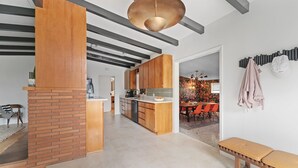 Een moderne keuken met houten kastjes, een centraal eiland en een eethoek met oranje stoelen.