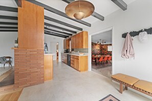 Eine moderne Küche mit Holzschränken, einer zentralen Kochinsel und einem Essbereich mit orangefarbenen Stühlen.