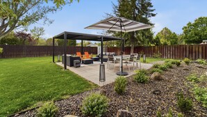 Een overdekt terras met buitenmeubilair, een tafel en een pergola.