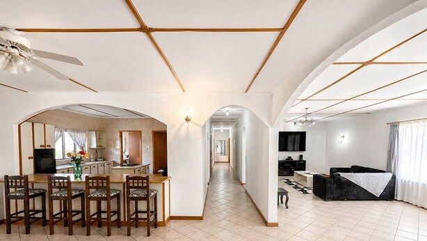 Amplia sala de estar con mesa de comedor, sillas, cocina y televisor.