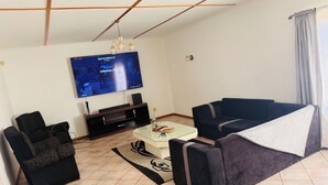 Una sala de estar con televisor de pantalla plana, sofá, sillón y una mesa de centro.