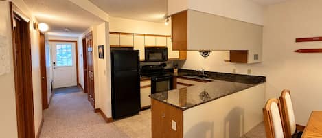 A compact kitchen with a central island, a microwave, a refrigerator, and a sink.