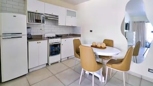 Une cuisine moderne avec des meubles blancs, une cuisinière et un coin repas comprenant une table ronde et quatre chaises.