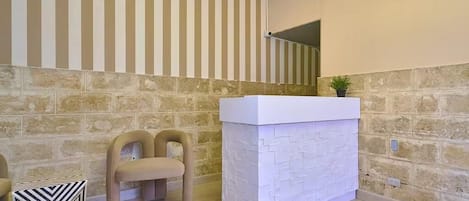 A reception area with a stone wall, a white reception desk, and a bench.