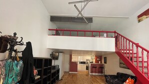 Un apartamento estilo loft con comedor, cocina y una escalera roja.