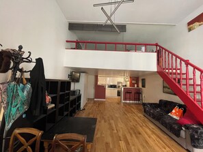 Eine Loft-Wohnung mit Essbereich, K üche und einer roten Treppe.