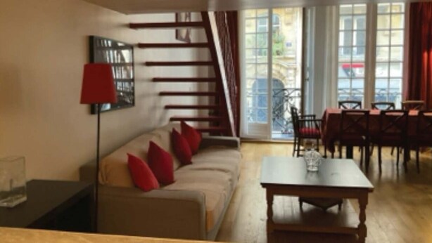 Una sala de estar con sofá, una mesa y una escalera.