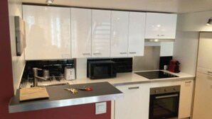 Una cocina moderna con armarios blancos, microondas, lavaplatos y horno.