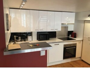 Eine moderne Küche mit weißen Schränken, einer Mikrowelle, einem Spülbecken und einem Backofen.