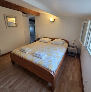 Ein Schlafzimmer mit einem hölzernen Bett, einem Nachttisch, einer Wandlampe und einem Spiegel.