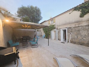 Ein überdachter Patio-Bereich mit Sitzgelegenheit und Grill.