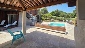 A covered outdoor area with a swimming pool, lounge chairs, and a staircase leading to a wooden deck. - CASA FUNTA - villa T5 - vue mer- piscine (Sainte Lucie Porto-Vecchio)