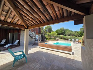 A covered outdoor area with a swimming pool, lounge chairs, and a staircase leading to a wooden deck. - CASA FUNTA - villa T5 - vue mer- piscine (Sainte Lucie Porto-Vecchio)