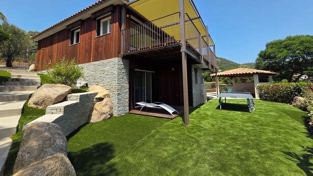 A modern house with a stone facade, a balcony, and a well-maintained lawn. - CASA FUNTA - villa T5 - vue mer- piscine (Sainte Lucie Porto-Vecchio)