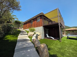Une maison moderne avec une façade en pierre, une terrasse en bois et une vue dégagée sur le paysage environnant.