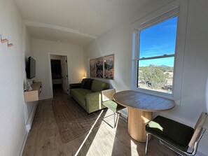 A compact living space with a dining area, a sofa, a TV, and a view of the outdoors. - Container Home at the Edge of the San Juans (South Fork)