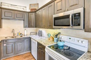 Eine Küche mit Granit Arbeitsplatten, Edelstahlgeräten und Holzschränken.