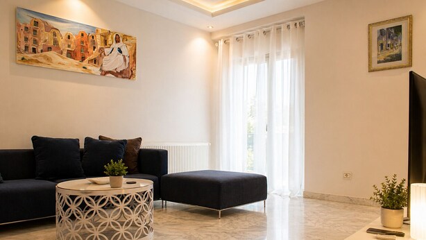A living room with a sofa, ottoman, coffee table, and a painting on the wall. - Luxury Oasis S 2 Comfort at the Garden in Carthage (Tunis)