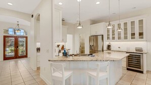 A modern kitchen with white cabinetry, a granite countertop, and pendant lighting. - Elegant 4-bed Home w/ Pool & Spa Near Siesta Key (Bee Ridge)