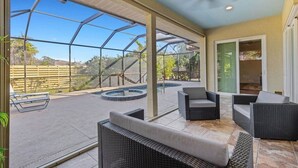A covered patio with outdoor seating, a pool, and a view of the surrounding landscape. - Elegant 4-bed Home w/ Pool & Spa Near Siesta Key (Bee Ridge)