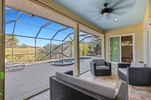 Eine überdachte Terrasse mit Sitzgelegenheiten im Freien, einem Pool und Blick auf die umliegende Landschaft.