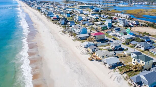 An aerial view of a coastal residential area with houses along the beach and a bridge in the background. - Huge Home- 1 min Walk to Beach- Perfect Location (Surf City)
