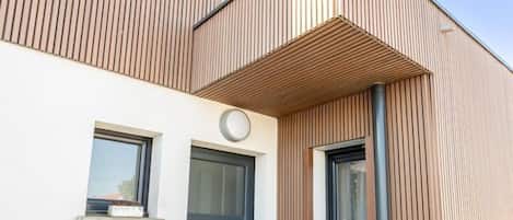 A modern building with a wooden facade, a small window, and a door.