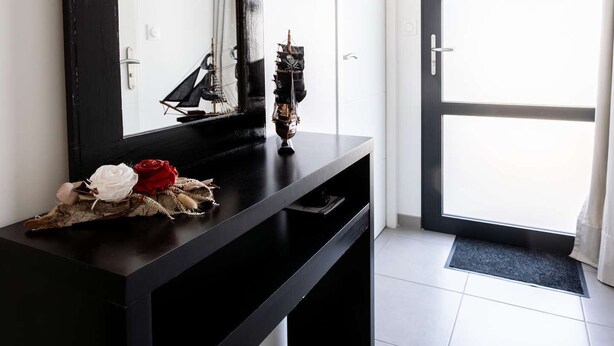 Um banheiro moderno com toucador preto, um espelho grande e uma miniatura decorativa de navio.