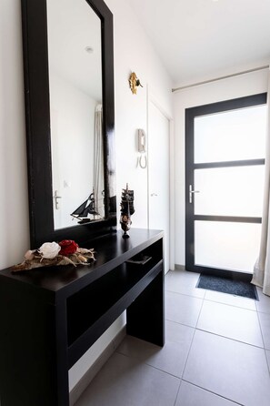 Un baño moderno con un tocador negro, un espejo grande y una maqueta decorativa de barco.