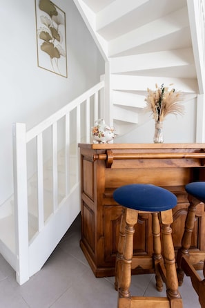 A staircase with white railings, a wooden bench with blue cushions, and a vase with dried flowers on the landing. - Maison climatisée avec jardin (BISCARROSSE)