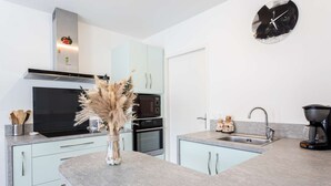 Uma cozinha moderna com forno embutido, micro-ondas e um vaso decorativo no balcão.