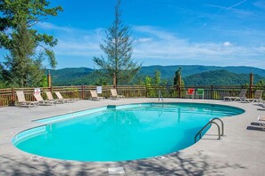 A rectangular swimming pool with a wooden deck, surrounded by lounge chairs and a wooden fence. - Rustic Pet Friendly Cabin in Pigeon Forge! (Pigeon Forge)