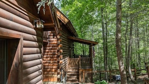 A log cabin with a porch, surrounded by a forest. - Rustic Pet Friendly Cabin in Pigeon Forge! (Pigeon Forge)