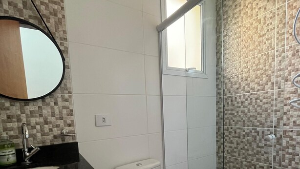 A bathroom with a toilet, sink, and mirror. - Comfort and Convenience: Furnished Apartment in the Zélia Region (Boituva)