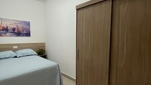 Un dormitorio con una cama, un armario, un cuadro en la pared y una lámpara en el techo.