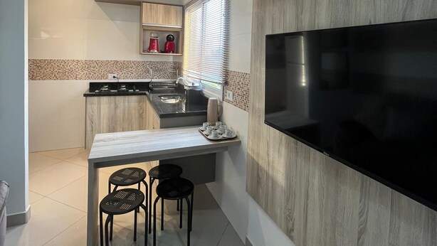 Una cocina moderna con televisor integrado, comedor con taburetes y una pequeña isla con pileta.