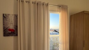 Una habitación con un ventanal grande, un armario de madera y un cuadro en la pared.