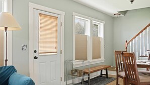 A room with a door, a bench, a chair, a table, and a lamp. - River Road Cottage · 2BR Near Trails & Downtown (Missoula)