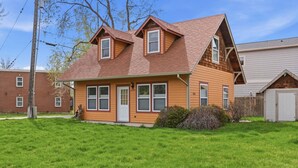A two-story house with a gabled roof, a front porch, and a small attached garage. - River Road Cottage · 2BR Near Trails & Downtown (Missoula)