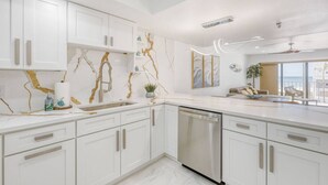 A modern kitchen with white cabinets, a stainless steel dishwasher, and a marble backsplash. - Oceanview Oasis w/ Balcony | Steps to the Sand (Madeira Beach)