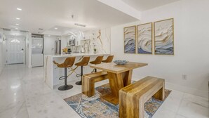 A modern kitchen with white cabinetry, a central island, and bar stools. - Oceanview Oasis w/ Balcony | Steps to the Sand (Madeira Beach)