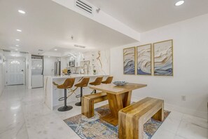 Una cocina moderna con armarios blancos, una isla central y taburetes de bar.
