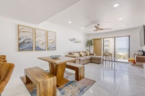Un salón moderno con una mesa de comedor de madera, un sofá color beige y un ventanal con vistas.