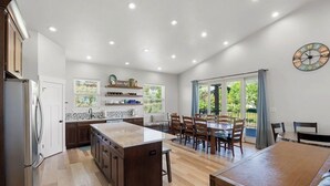 A spacious kitchen with a central island, wooden cabinets, and a dining area with a table and chairs.