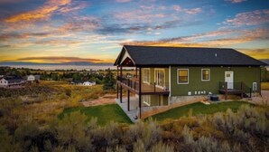 A house with a porch, a deck, and a view of the surrounding landscape.