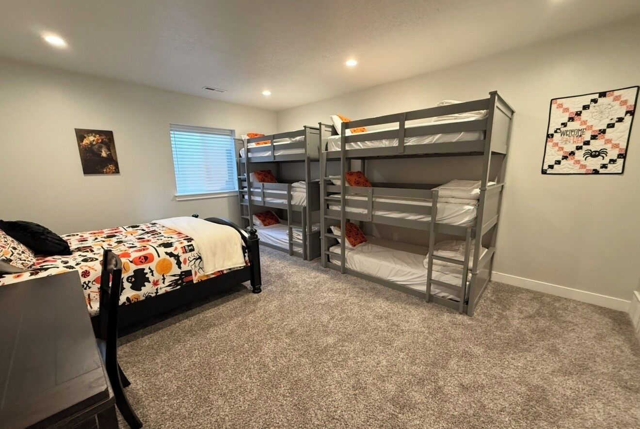 A room with bunk beds, a desk, and a window with blinds.